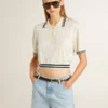 Kürzliches, im Used-Look gehaltenes Damen-Polohemd aus weißer Baumwolle mit blauen Rippbündchen