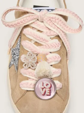 Schnürsenkel aus Lederwaren in Hellbeige mit rosa Zierband, Anstecknadel und Applikationen